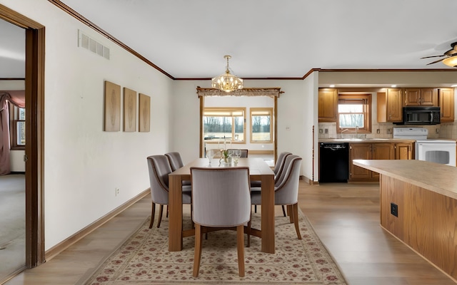 dining space with crown molding, light wood-style flooring, visible vents, and baseboards