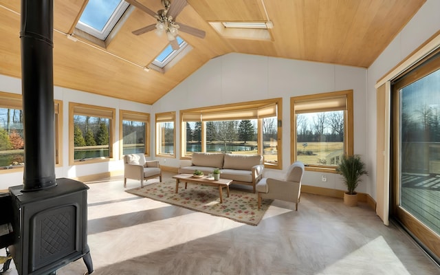 sunroom / solarium featuring vaulted ceiling with skylight, a ceiling fan, wooden ceiling, and a wood stove