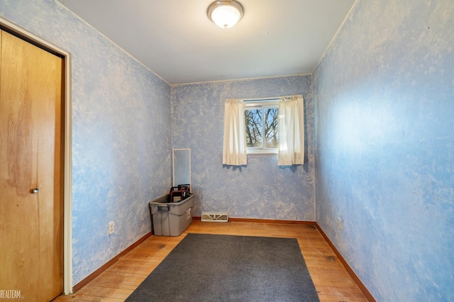 empty room featuring visible vents, baseboards, wood finished floors, and wallpapered walls