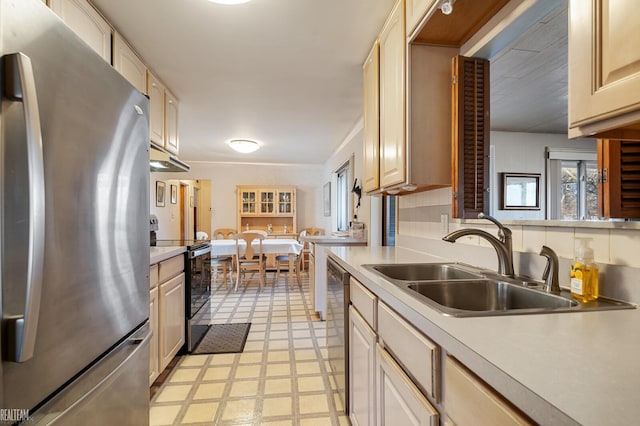 kitchen featuring light brown cabinets, a sink, stainless steel appliances, light countertops, and light floors