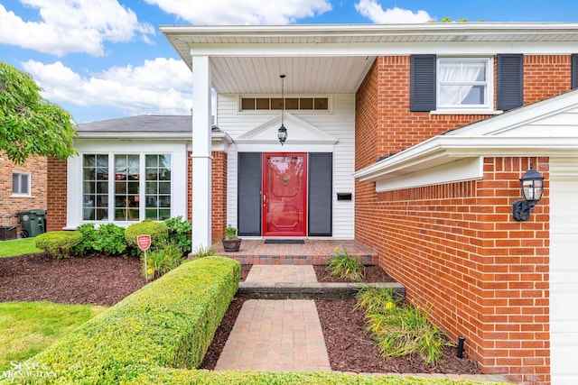 view of exterior entry featuring a garage and brick siding