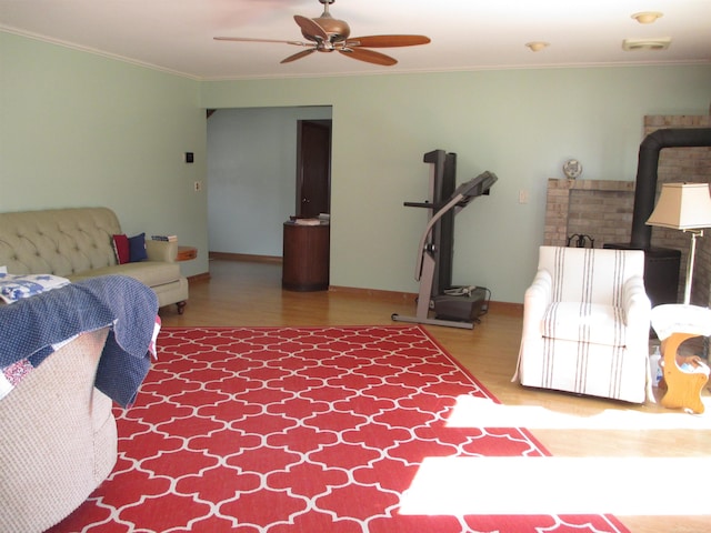 living room with baseboards, crown molding, ceiling fan, and wood finished floors