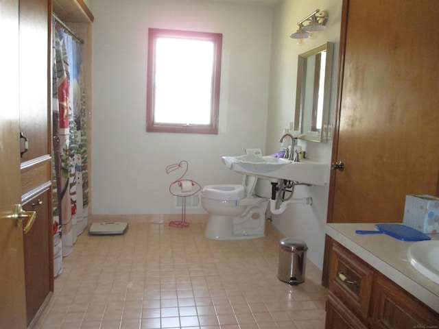 bathroom with curtained shower, toilet, baseboards, and a sink