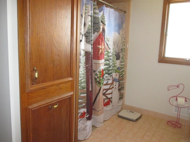 interior space with tile patterned floors, curtained shower, and baseboards