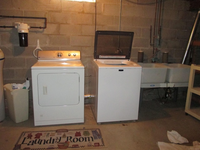 clothes washing area with washer and dryer, concrete block wall, and laundry area