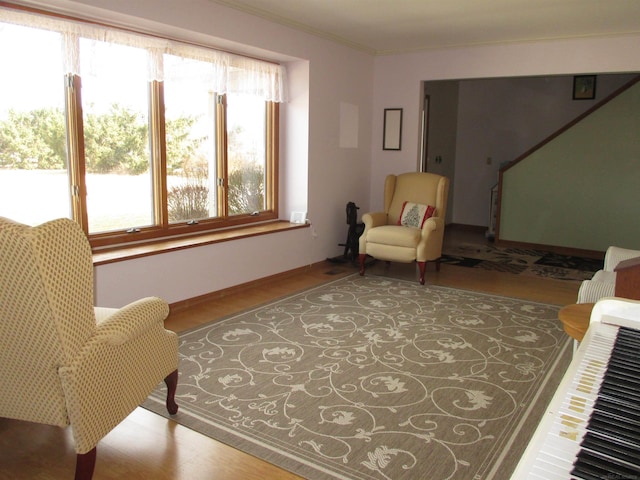 sitting room featuring baseboards, wood finished floors, a healthy amount of sunlight, and ornamental molding