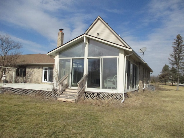 back of house with a yard, a sunroom, and a chimney