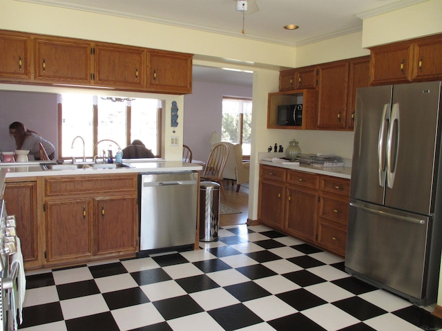 kitchen featuring light floors, light countertops, ornamental molding, appliances with stainless steel finishes, and a sink