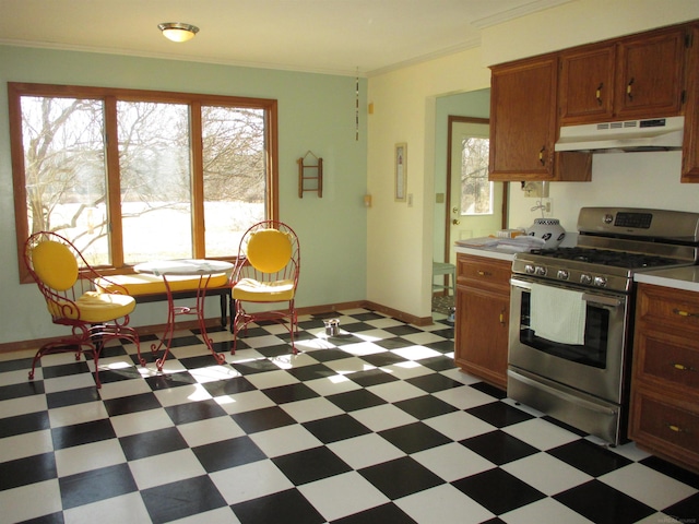 kitchen featuring light floors, ornamental molding, light countertops, under cabinet range hood, and gas range