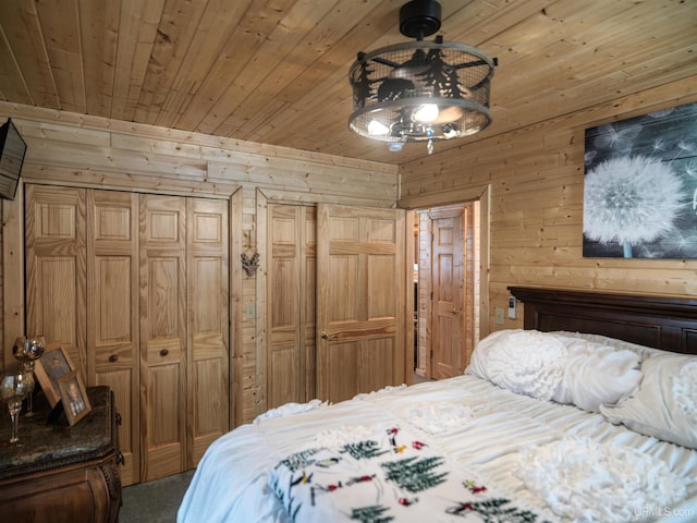 bedroom with wooden walls, wooden ceiling, two closets, and ceiling fan