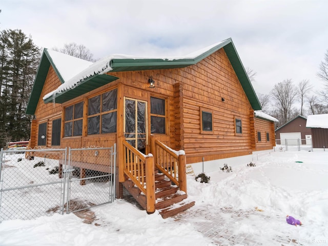 view of front of home with a detached garage, fence, log exterior, an outbuilding, and a gate