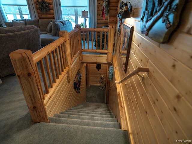 staircase featuring a wealth of natural light and rustic walls