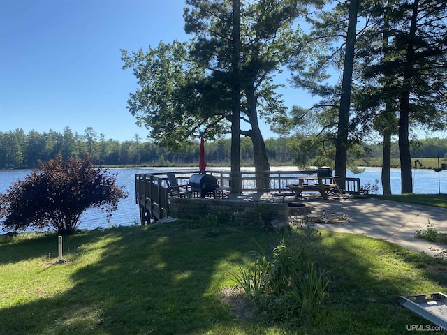 view of dock with a yard and a water view