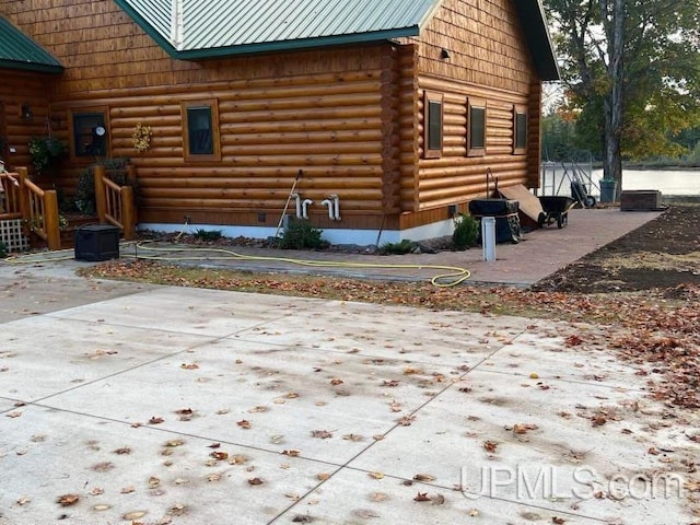 view of side of property featuring log siding and metal roof