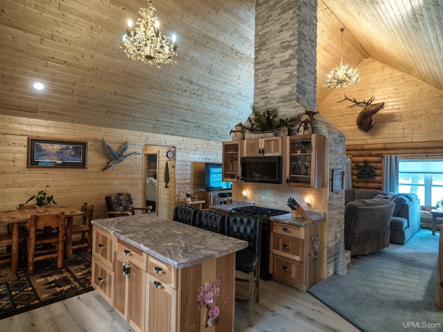 kitchen with high vaulted ceiling, black appliances, a kitchen bar, light wood-type flooring, and a chandelier