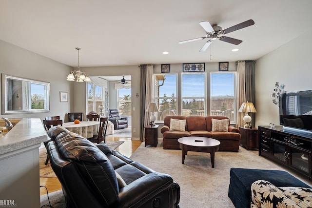 living area with recessed lighting, ceiling fan with notable chandelier, and light colored carpet