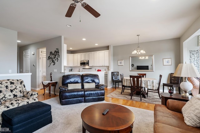 living room with recessed lighting, light wood-type flooring, baseboards, and ceiling fan with notable chandelier