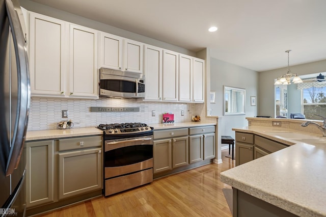 kitchen featuring a sink, stainless steel appliances, light wood-style flooring, and decorative backsplash