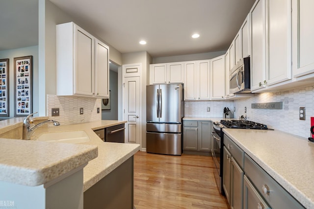 kitchen featuring light wood-style flooring, recessed lighting, a sink, stainless steel appliances, and light countertops