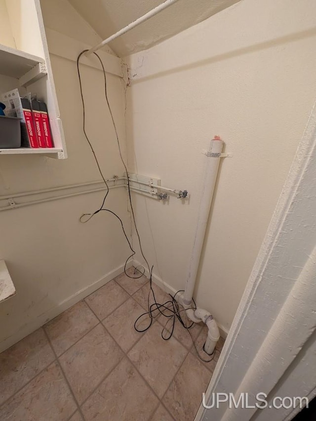 laundry area with light tile patterned flooring and baseboards