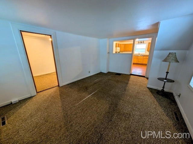 interior space with a sink, baseboards, carpet floors, and visible vents