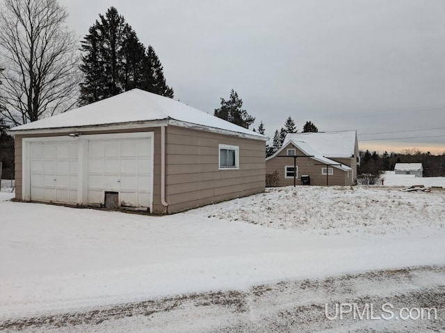 snow covered garage with a detached garage