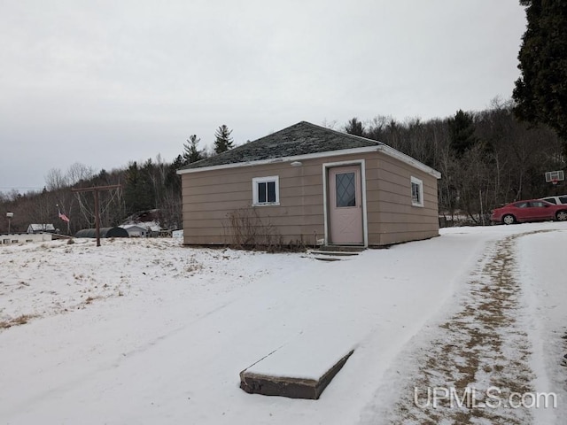 snow covered structure featuring an outbuilding