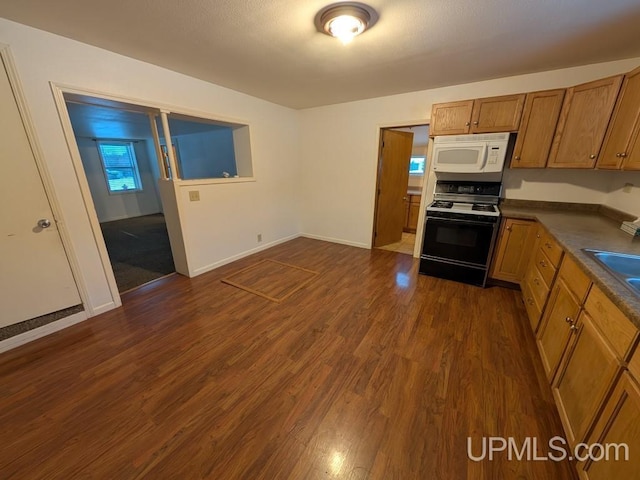 kitchen with range with gas stovetop, dark countertops, dark wood-style floors, and white microwave