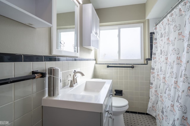 full bath featuring a shower with shower curtain, toilet, tile walls, and vanity