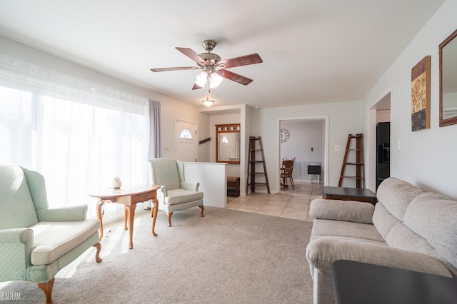 living area featuring light tile patterned flooring, a ceiling fan, and light carpet