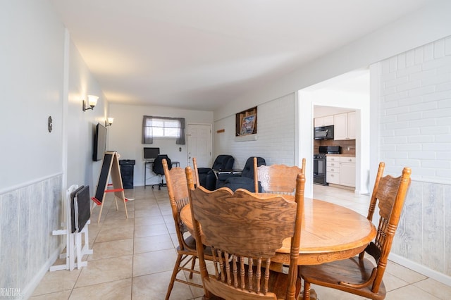 dining room with light tile patterned floors and a wainscoted wall