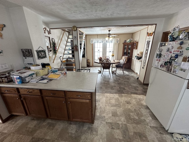 kitchen with stone finish floor, a textured ceiling, freestanding refrigerator, and light countertops