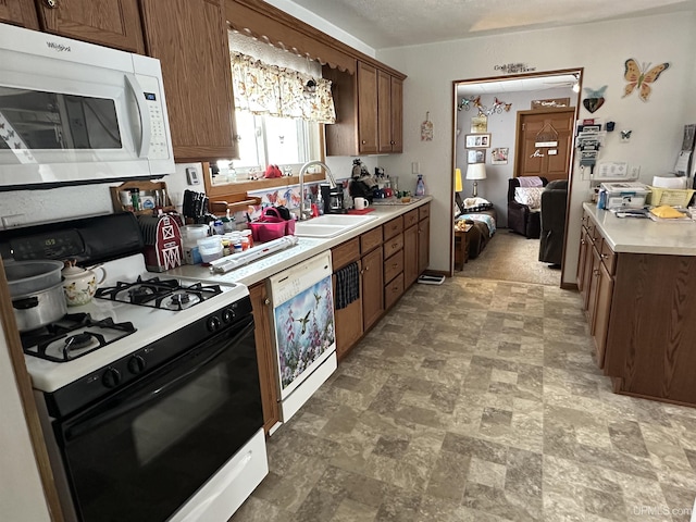 kitchen featuring dishwashing machine, gas stove, white microwave, a sink, and light countertops