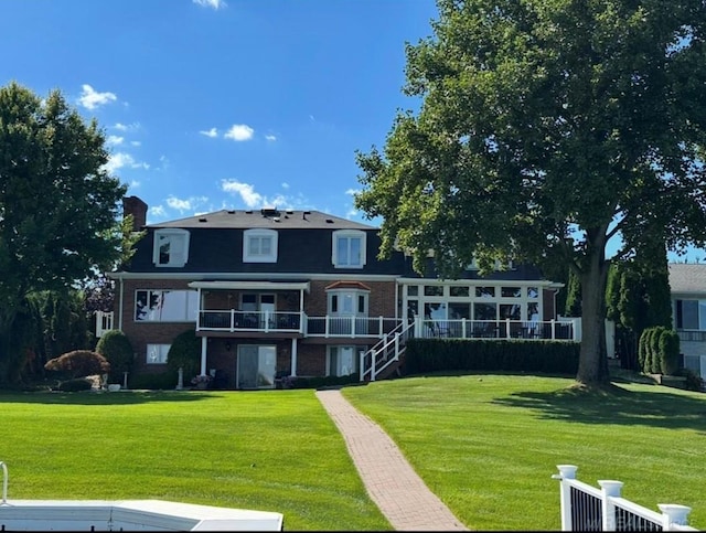 rear view of house with brick siding, a chimney, and a yard