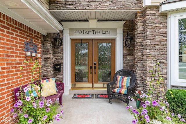 property entrance with brick siding, french doors, and stone siding