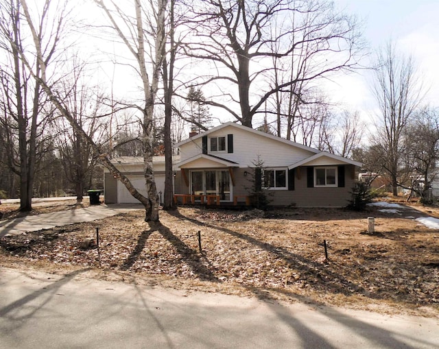 view of front facade featuring driveway, an attached garage, a porch, and a chimney