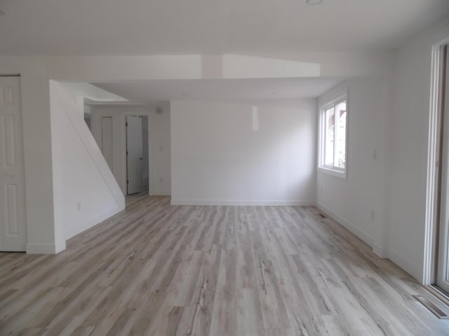 unfurnished living room with light wood-style flooring, visible vents, and baseboards