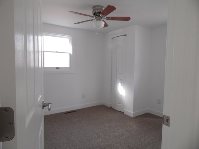 spare room featuring visible vents, light colored carpet, baseboards, and ceiling fan