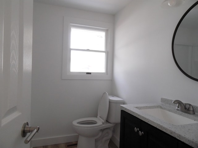 half bath with vanity, toilet, and visible vents