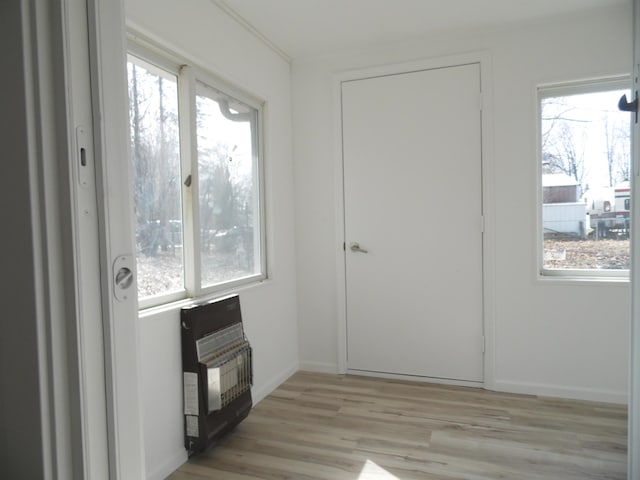 interior space featuring heating unit, light wood finished floors, and baseboards