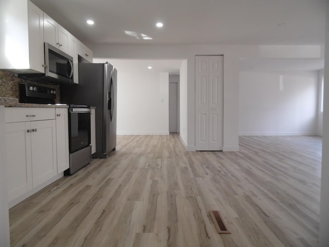 kitchen with stainless steel microwave, open floor plan, electric range oven, and white cabinetry