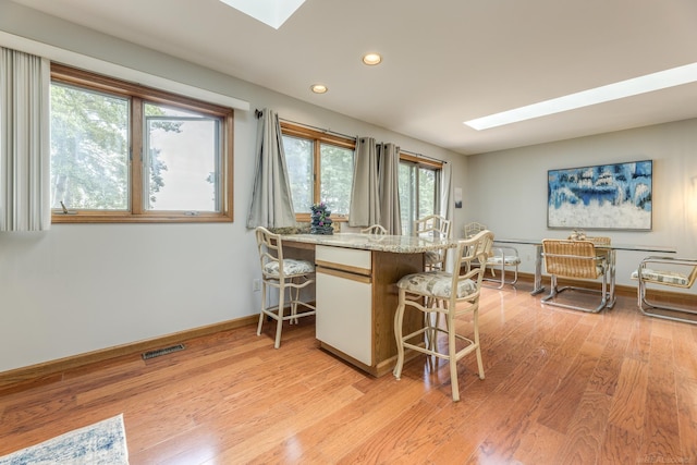 kitchen featuring visible vents, a kitchen breakfast bar, a skylight, and light wood-style flooring