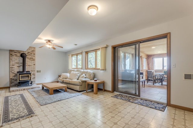 living area featuring visible vents, baseboards, light floors, and a wood stove