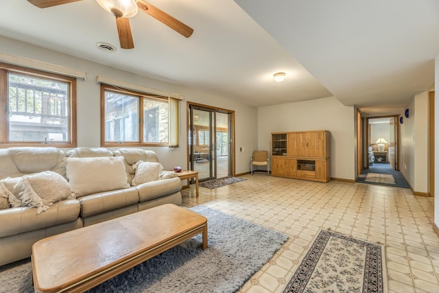 living area with ceiling fan, light floors, visible vents, and baseboards