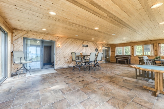 unfurnished dining area featuring wooden walls, recessed lighting, wood ceiling, and stone finish floor