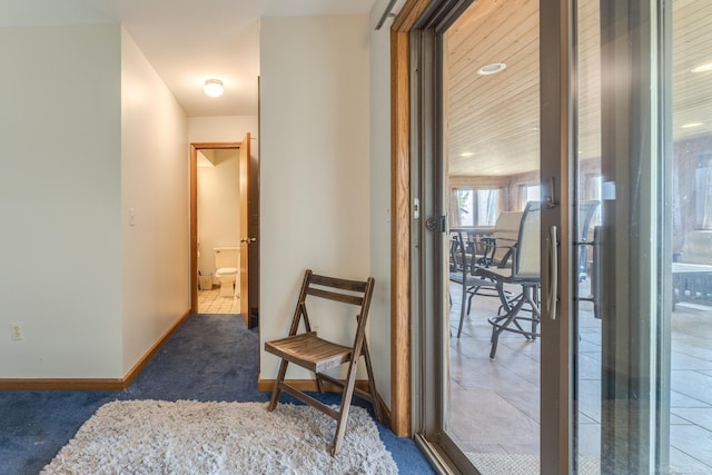 corridor featuring baseboards and carpet floors