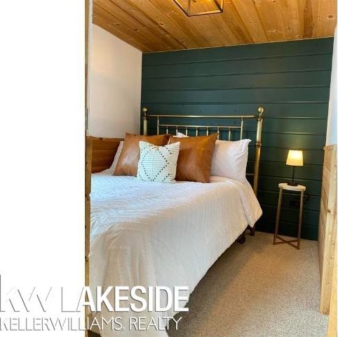 carpeted bedroom with wooden walls and wood ceiling