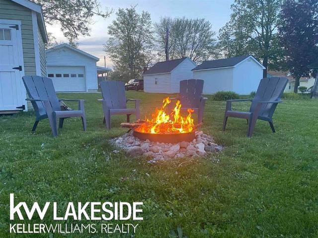 view of jungle gym featuring a lawn, an outdoor structure, and an outdoor fire pit