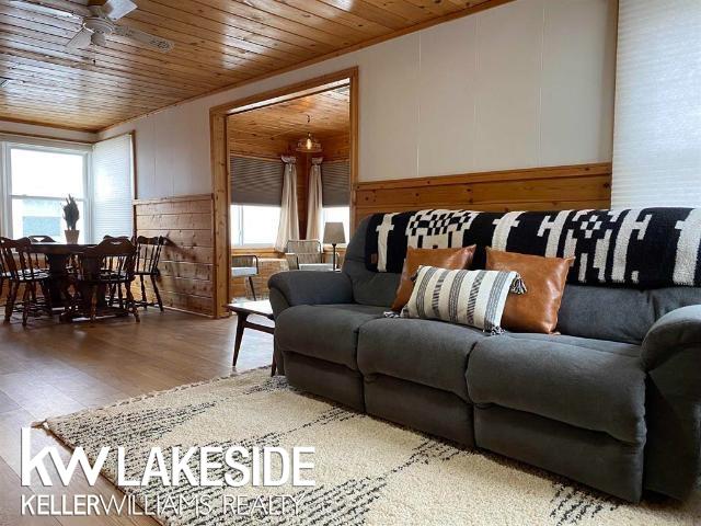 living room featuring a ceiling fan, wood finished floors, and wood ceiling