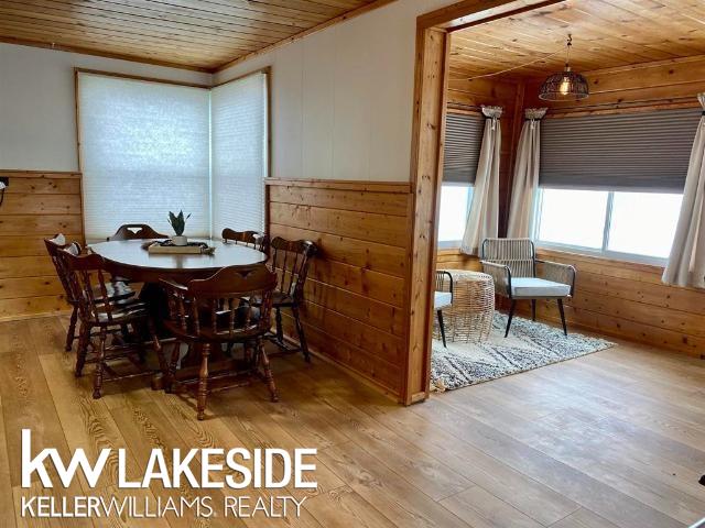 dining room with wooden walls, wood ceiling, and wood-type flooring